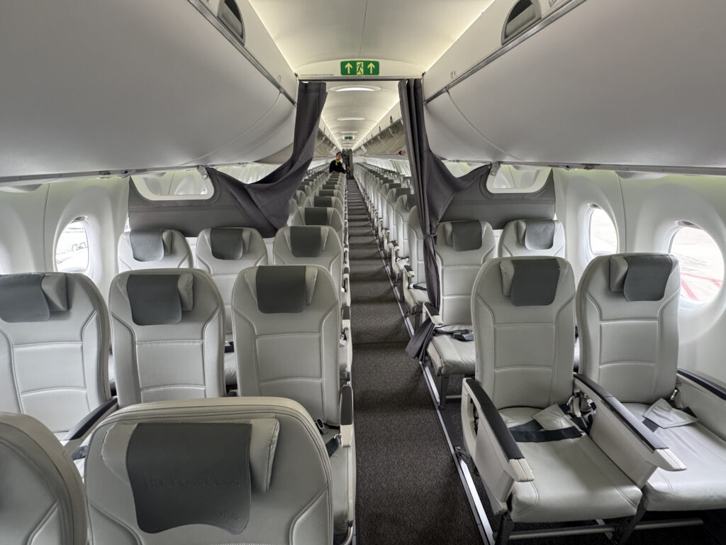 AirBaltic A220 cabin interior, configured 2-3 with light grey seats and dark grey headrest covers.
