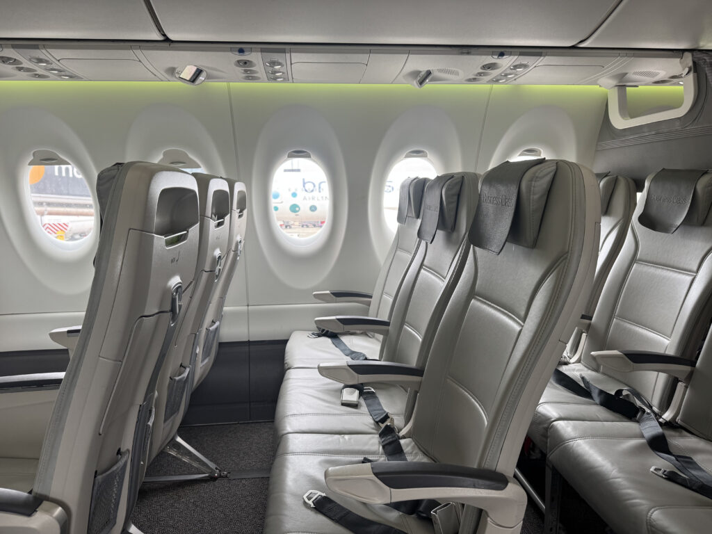 Side view of airBaltic A220 cabin with green LED lighting casting a pretty glow on the sidewall. 