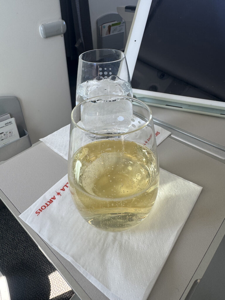 Cava served by Brussels Airlines sits on the tray table alongside a sparkling water. 