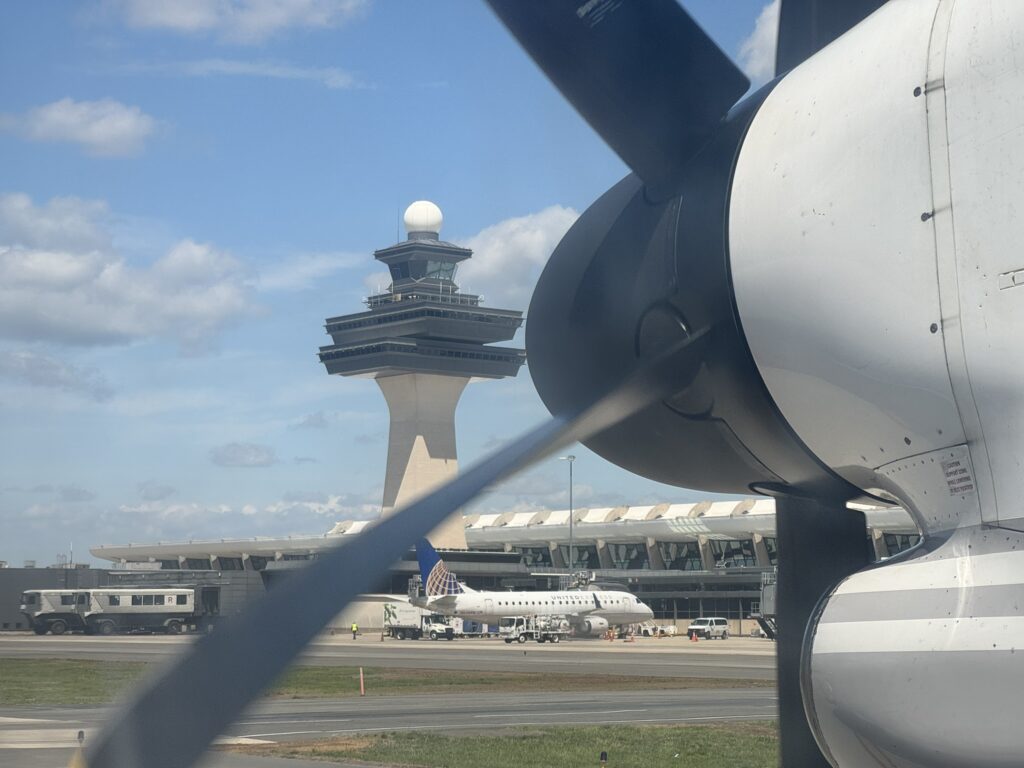 Close up of Q400 engine, with IAD's legacy ATC tower in the distance.