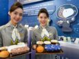 Two STARLUX flight crew members hold PEANUTS themed meals