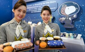 Two STARLUX flight crew members hold PEANUTS themed meals