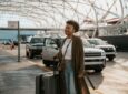 A woman is arriving at an airport with baggage in hand
