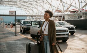 A woman is arriving at an airport with baggage in hand