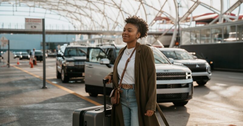 A woman is arriving at an airport with baggage in hand