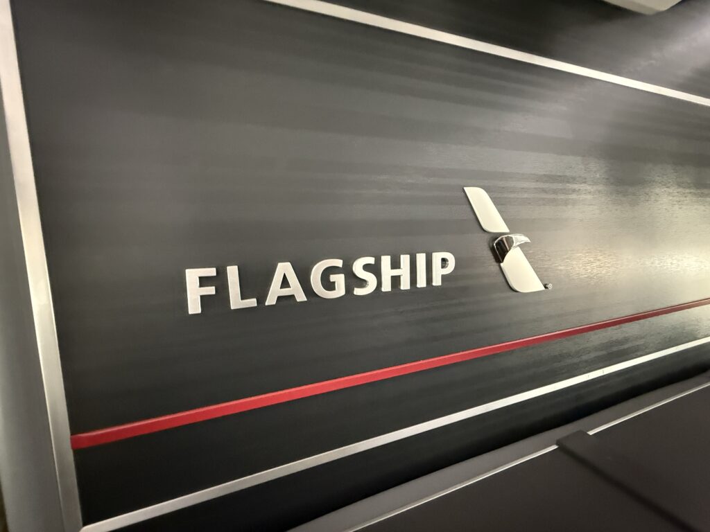 A black ribbed wall bearing the backlit “Flagship” wordmark and AA Flight Symbol