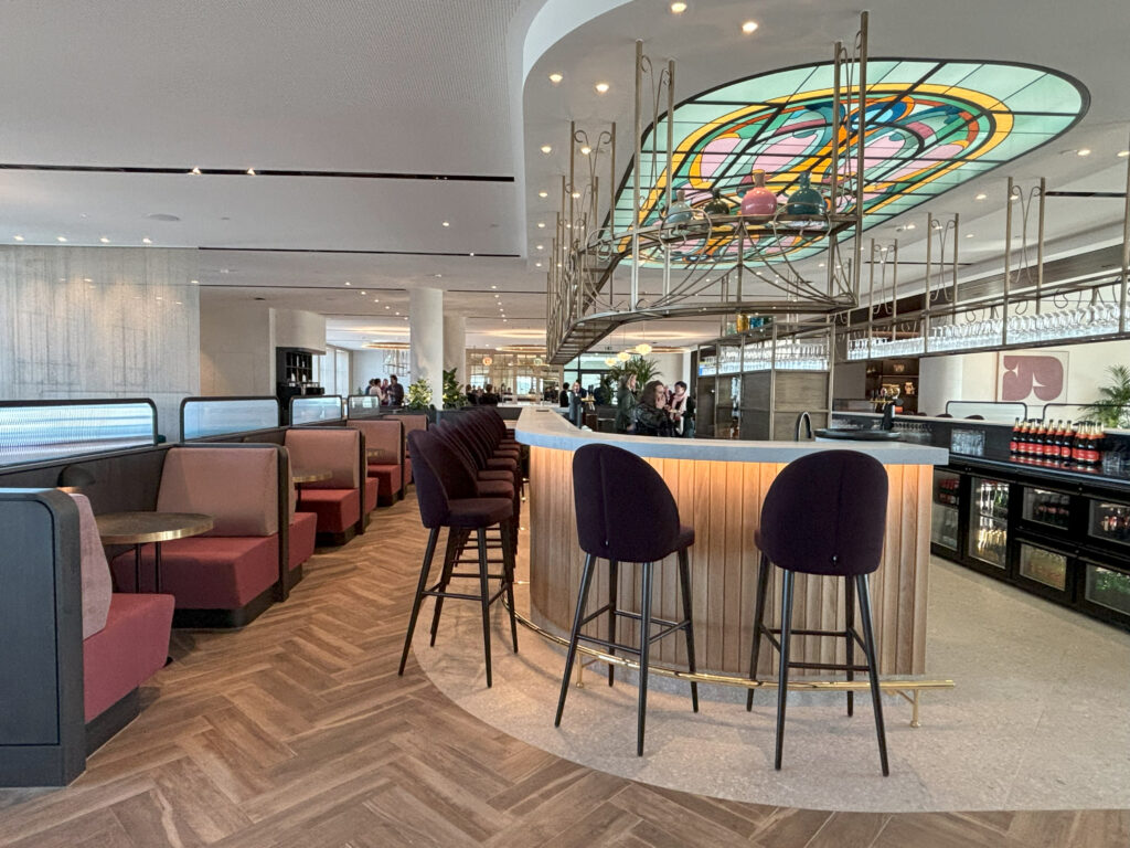 Bar with spectacular stained glass above it in the lounge. Two-person booths are seen beside the bar.