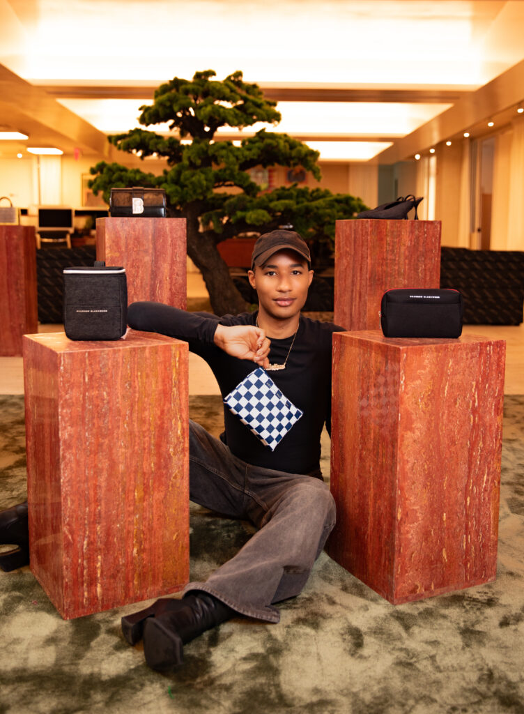 Designer Brandon Blackwood sitting with his amenity kits for American Airlines.