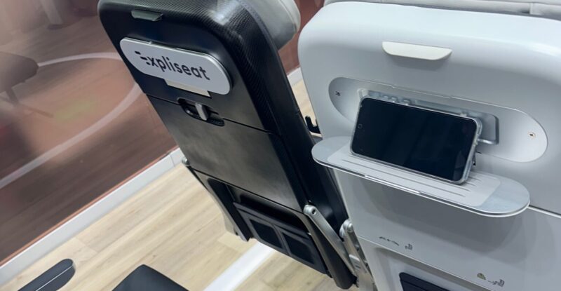 Close up of the Expliseat seat and PED holder on the AIX show floor. The word Expliseat is on the seatback of one of the seats.