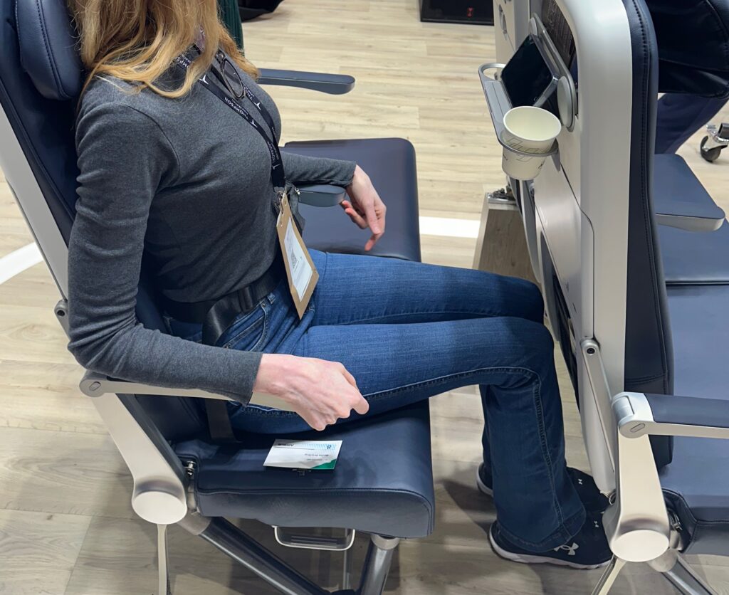 Author Mary Kirby sitting in the TiSeat 2X by Expliseat on the AIX show floor.