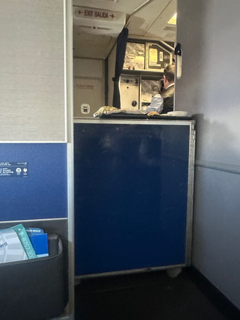Galley cart blocks the entrance to the forward galley, creating a barrier between the cabin and cockpit on a United 757.