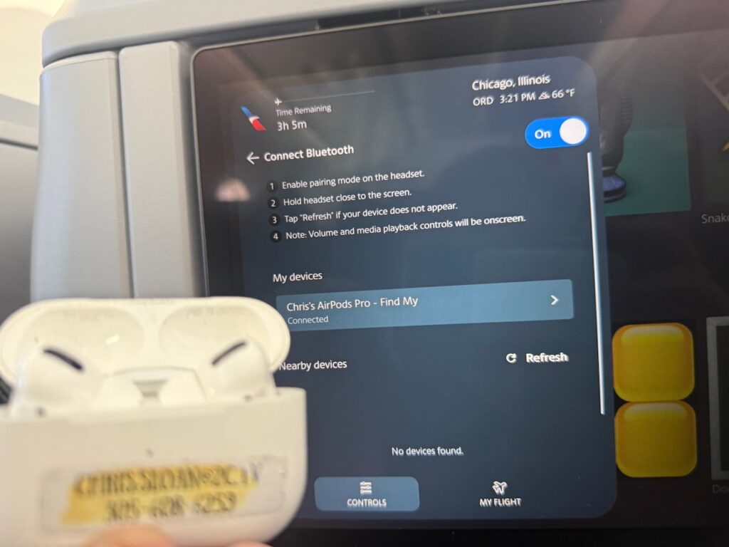 The author holds up his AirPods to the IFE screen. 