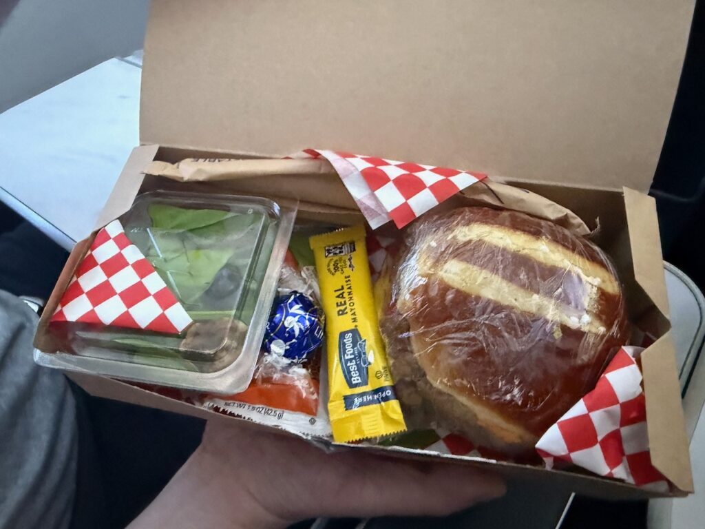 A sandwich, salad and various sides boxed up and available for purchase.