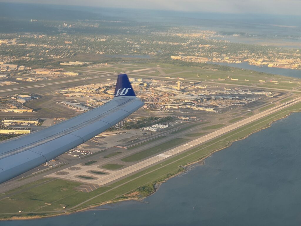 Climb out over New York with beautiful views, and a blue wingtip in view through a cabin window.