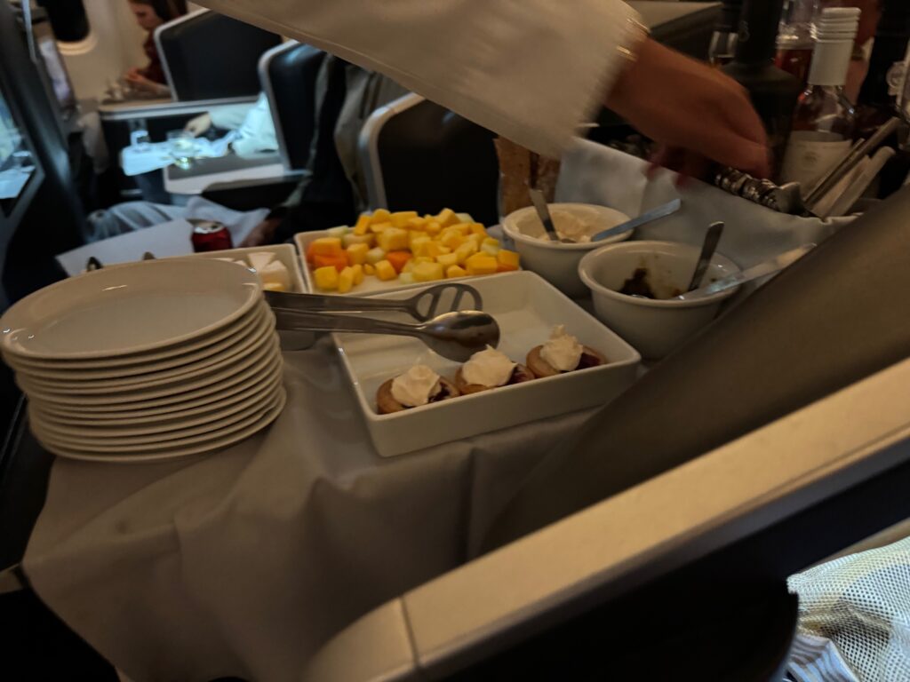 Fruit and mini cheesecakes are atop the trolley, as crew members dispense dessert.