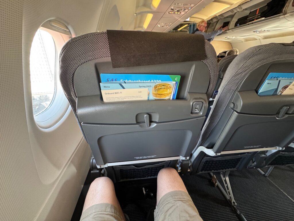 The author's legs as seen in relation to the seatback. He has perhaps an inch of knee clearance.