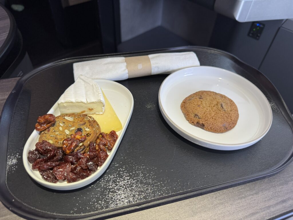 A cookie and cheese plate are displayed on the aircraft tray table