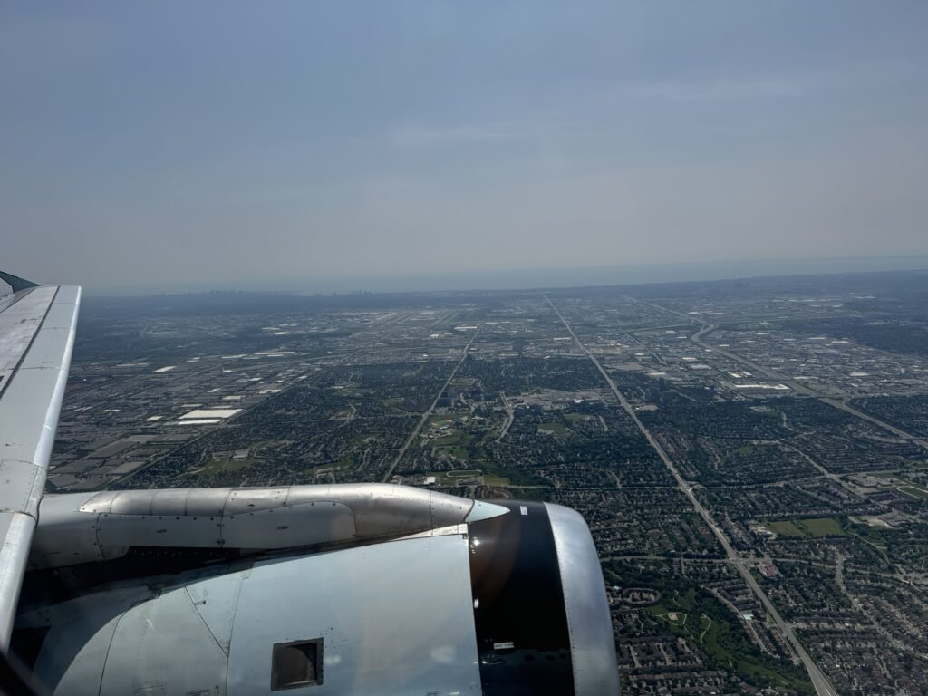 Looking out the cabin window at the engine of the aged A320 as it flies over fields and roads.