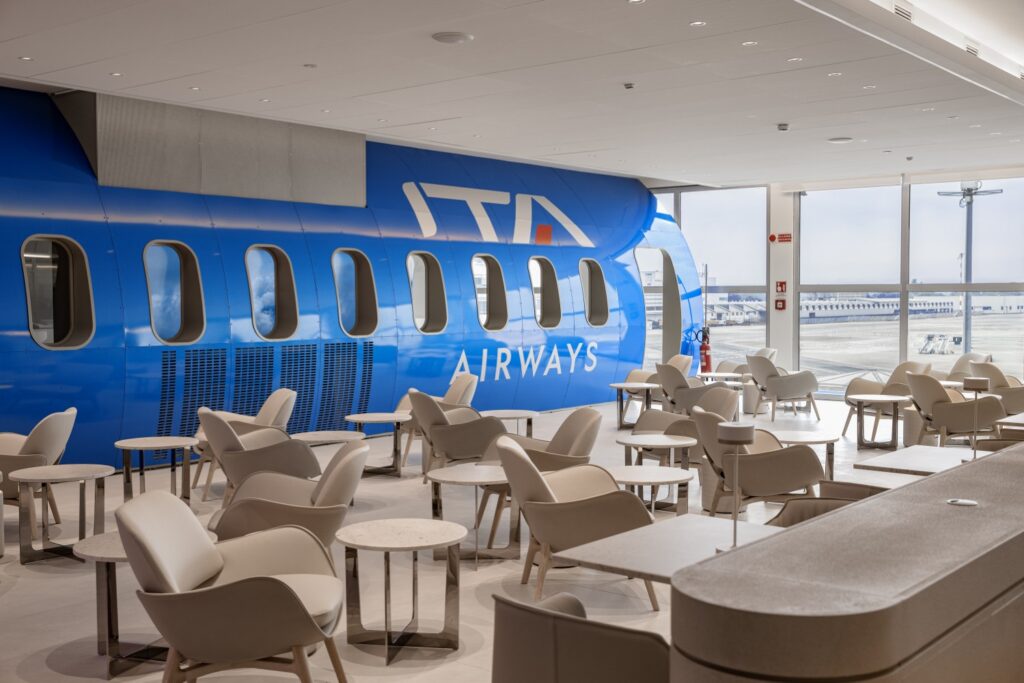 ITA Airway' Runway Lounge at Linate airport by Lufthansa Group features the side of a fuselage of an ITA Airways aircraft.