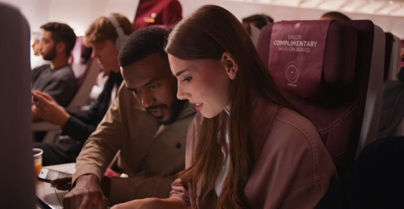 A woman uses Starlink IFC in-flight on a Qatar Airways widebody.