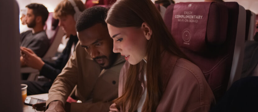 A woman uses Starlink IFC in-flight on a Qatar Airways widebody.