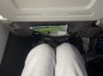 A woman's knees are seen a a short distance from the seat in front of her in economy class on an Aer Lingus flight