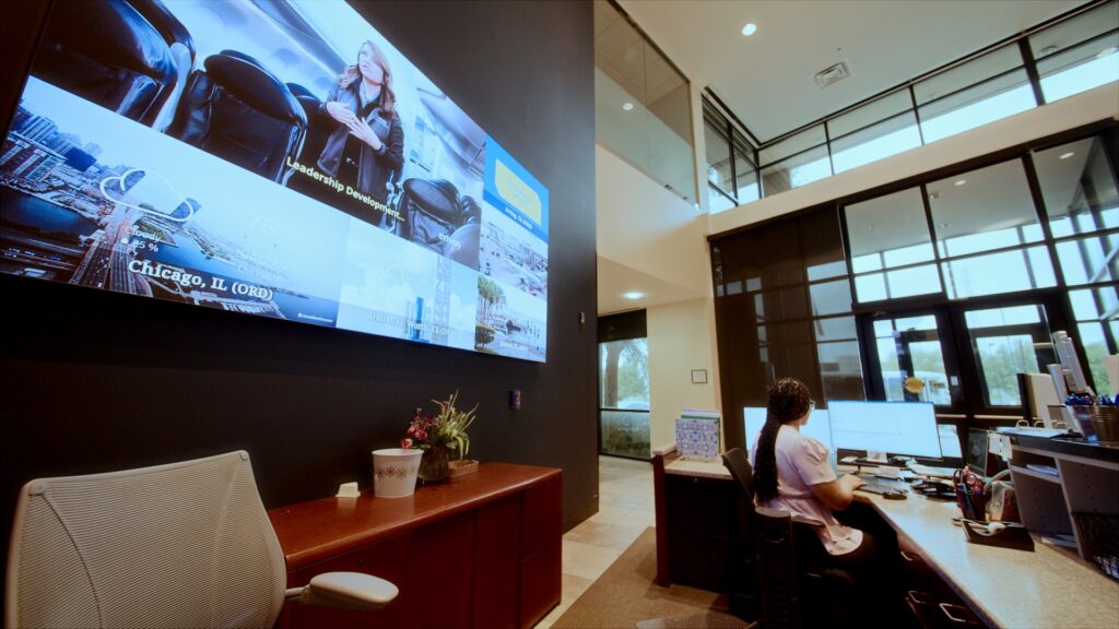 Giant Samsung display is seen behind a woman at the front desk.