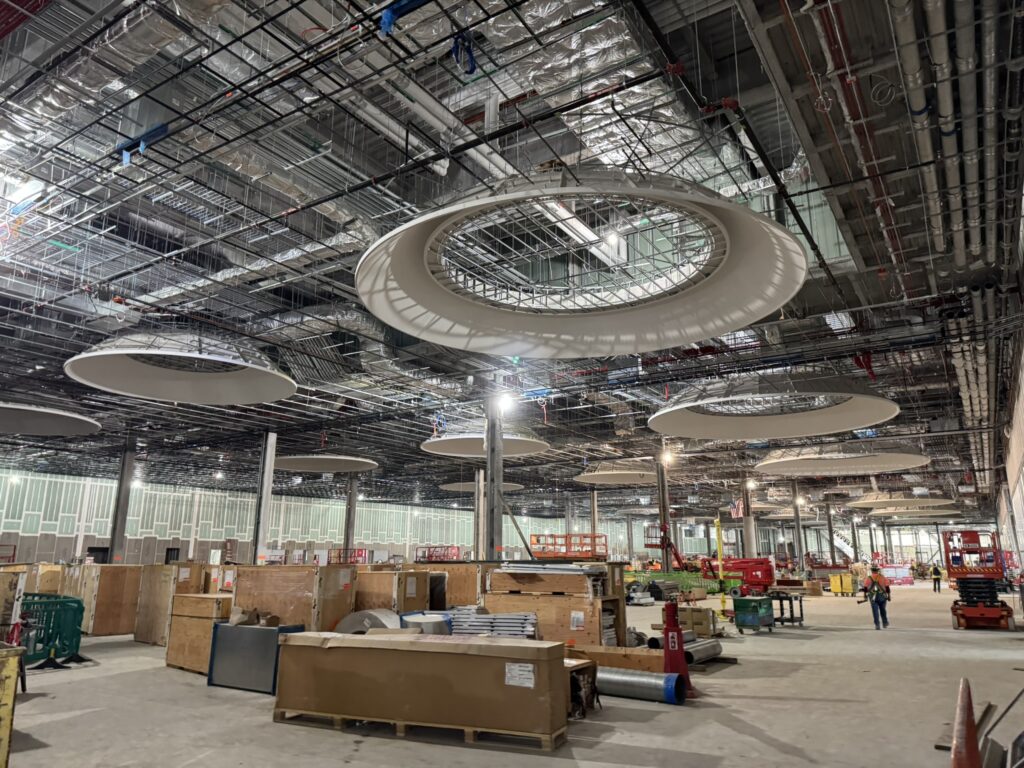 Inside the New Terminal One with large ceiling fixtures suggesting that artistic lighting or art installations are forthcoming.