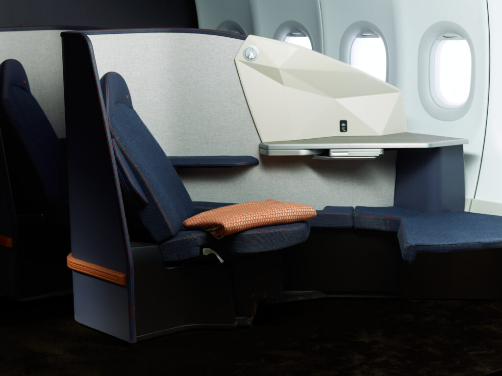 A close up of an empty OPERA ESSENTIAL seat in blue with white thermoplastic casing.