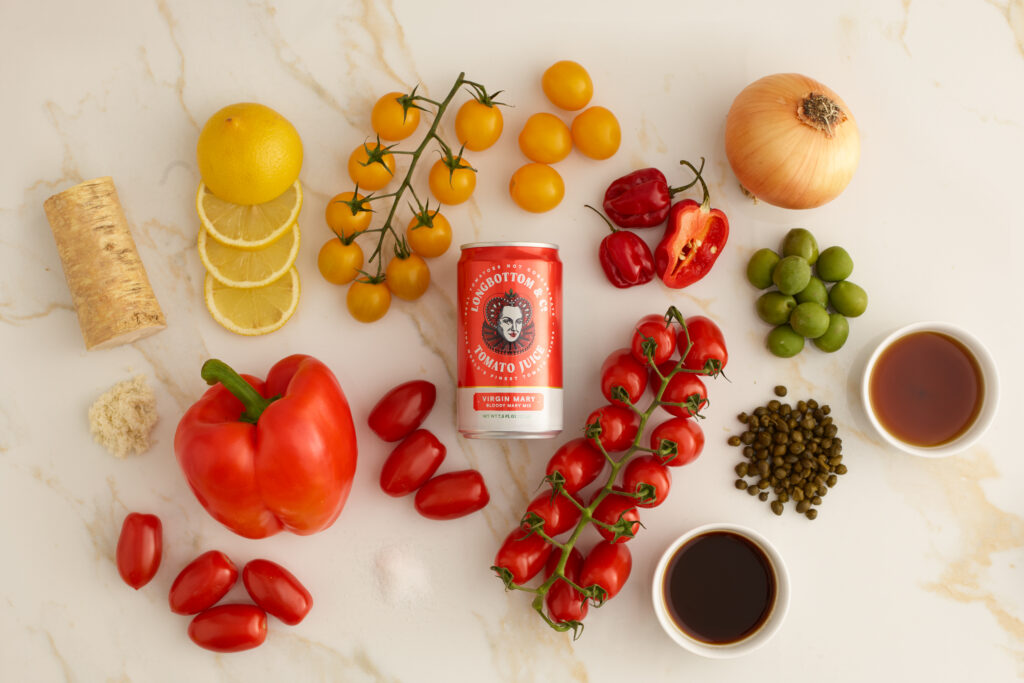 A variety of tomatoes around a can of tomato juice