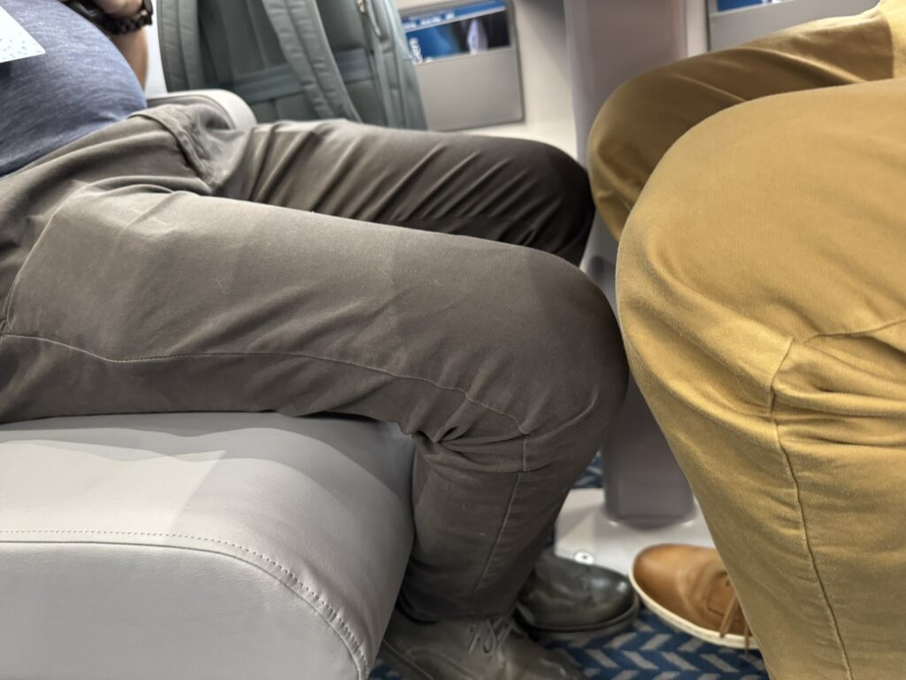 Two passengers knees touch in the seats on the Acela