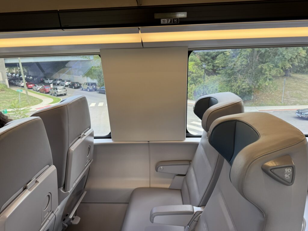 A close up of 2 seats on the train show all gray with subtle blue headrests. 
