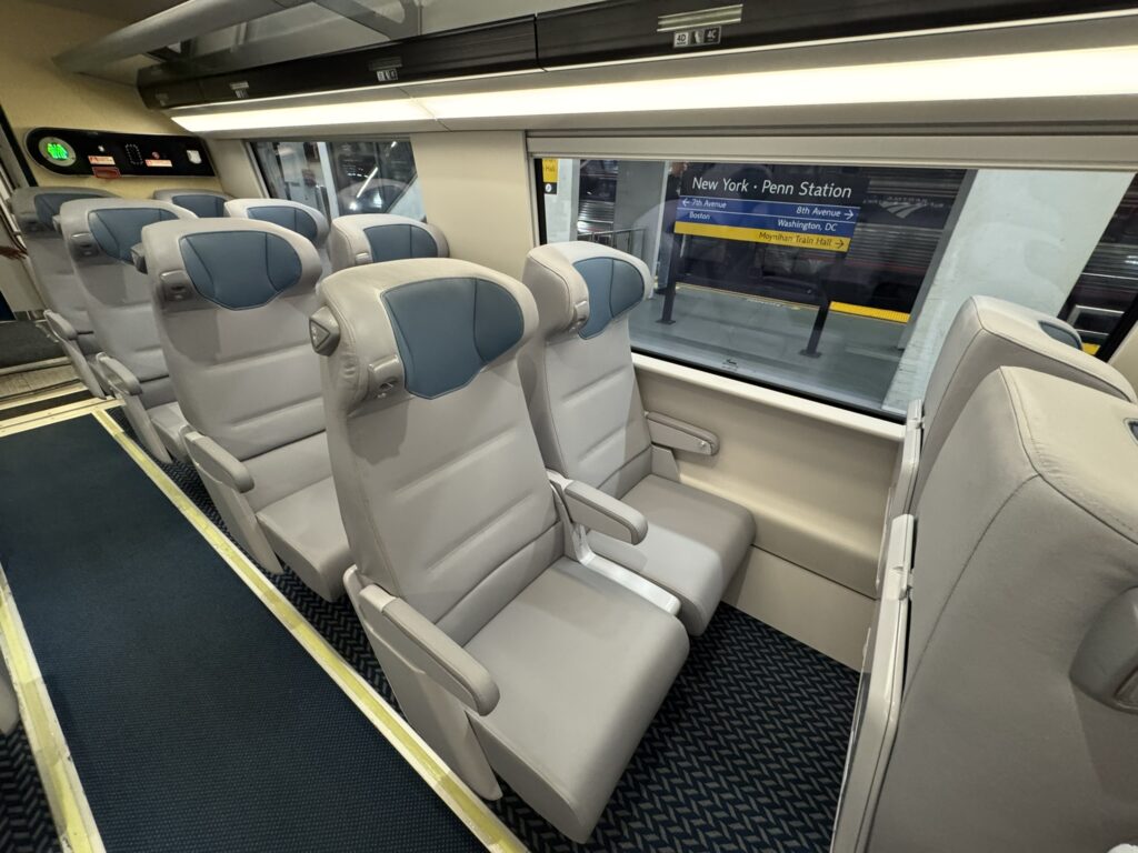 A set of two Acela seats in all grey with blue headrests. 