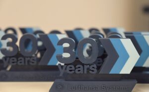 The words "Lufthansa Systems 30 years" are seen in block letters on a table