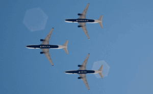 Three Delta aircraft in flight and each belly has the name of a destination on it, Sardinia. Malta, Ibiza.
