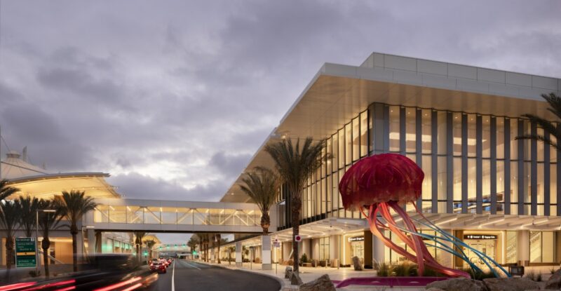 Outside facade of San Diego International Airport Terminal 1 arrivals building, featuring lots of glass and artwork.