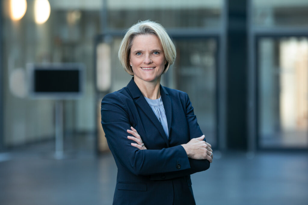 Nicole Dreyer-Langlet with her arms crossed posing for a photo in a suit