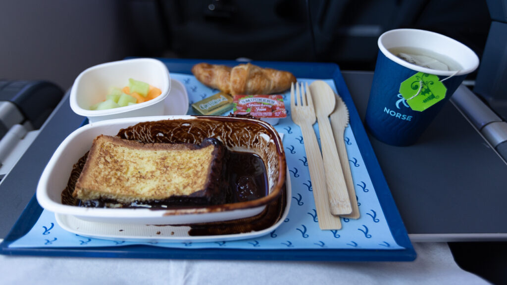 French toast was served and is displayed half eaten on the aircraft tray table. 