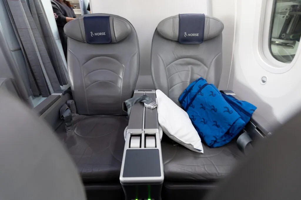 A pillow and blue blanket sit on an empty aircraft seat.