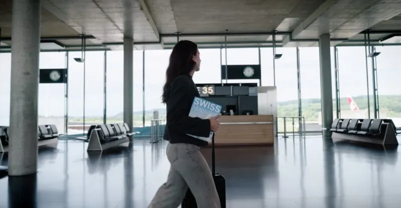 A passenger is carrying a copy of SWISS Magazine through the airport.