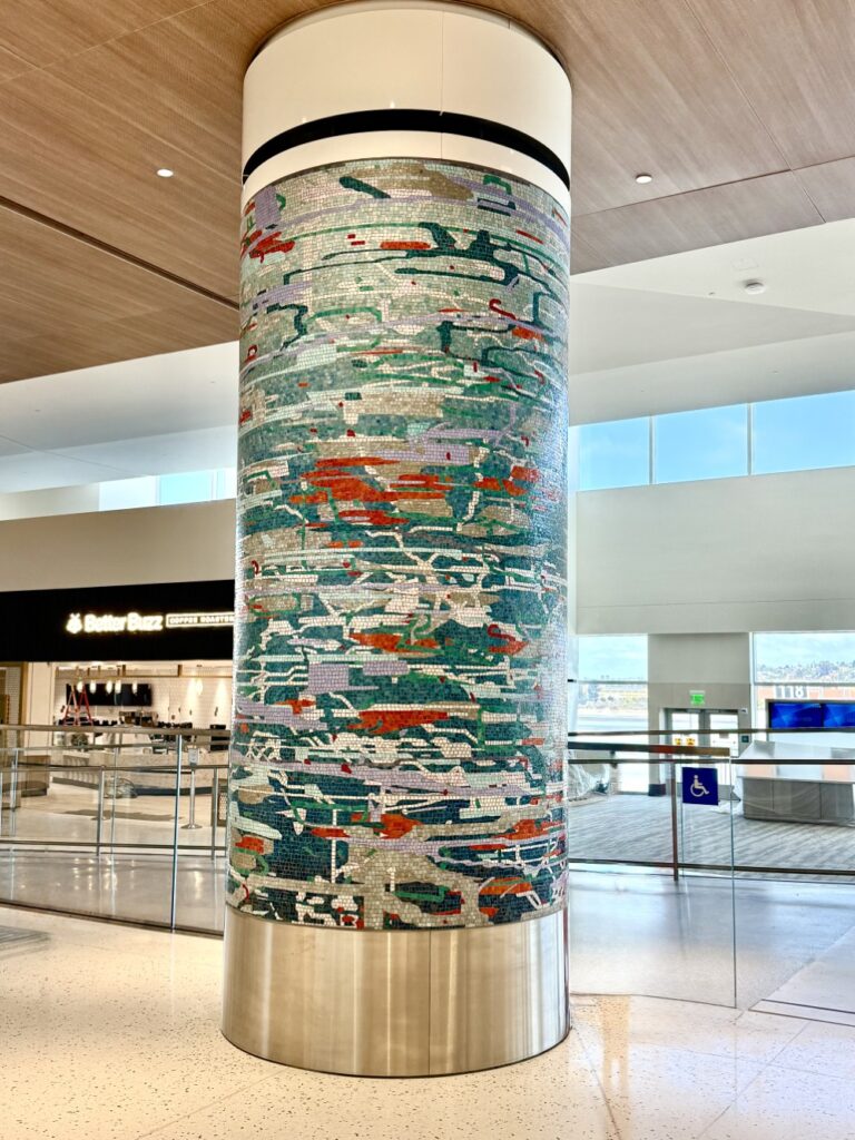 A column in the airport is covered in a mosaic that showcases many blues.