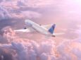 United Airlines Boeing 777 inflight above pink clouds.