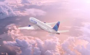 United Airlines Boeing 777 inflight above pink clouds.