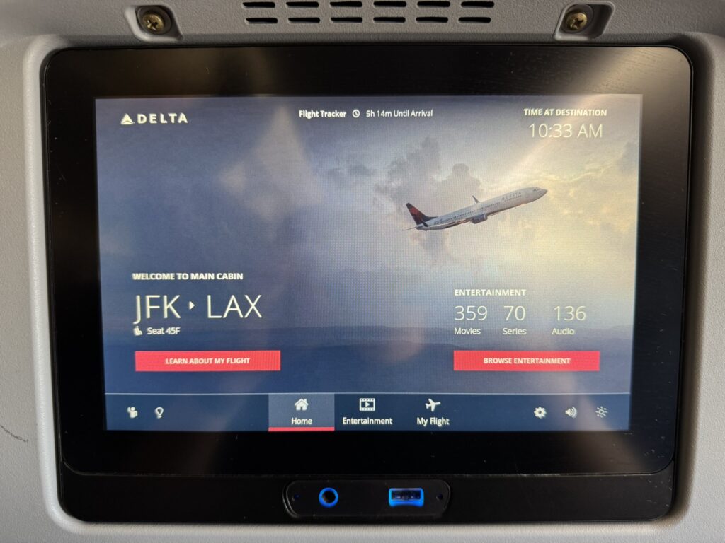 Delta's i- seat IFE shows a welcome page with trip information for the passenger.