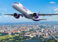 Rendering of E2 in Avelo livery flying over a town and a body of water