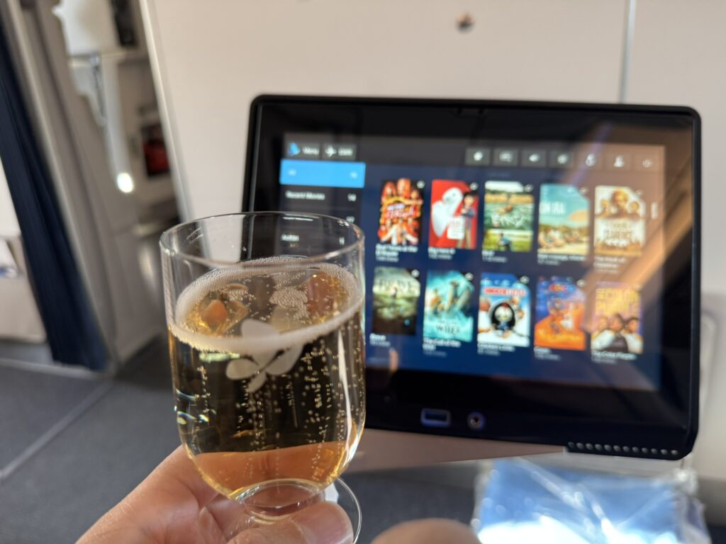 The passenger is holding up a glass of bubbly. 