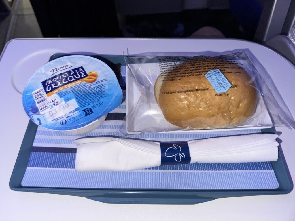Plastic sealed bread roll and peach flavored yogurt