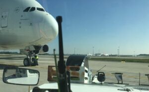 A tug vehicle is front of an Airbus A380 on the ramp