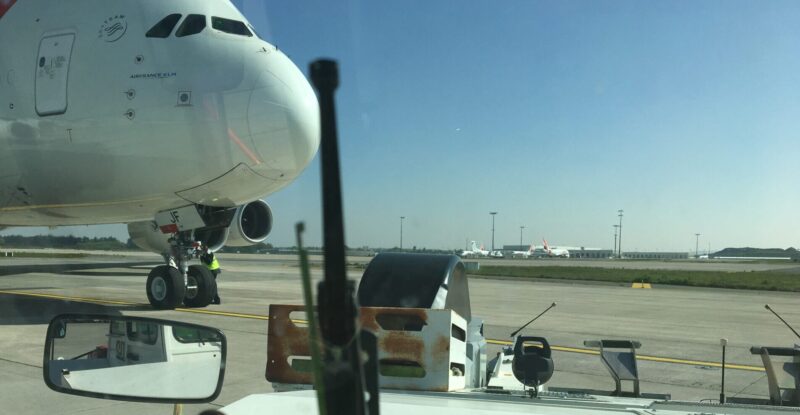 A tug vehicle is front of an Airbus A380 on the ramp