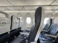 Smartwings Airbus A220-300 cabin with seats, PSUs and the bottom part of the current pivot bins in view.